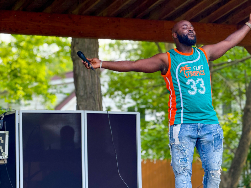 Flint artist and now community organizer G-S tha DreaM stands with his arms wide open during his closing performance at a Juneteenth festival on June 8, 2025.