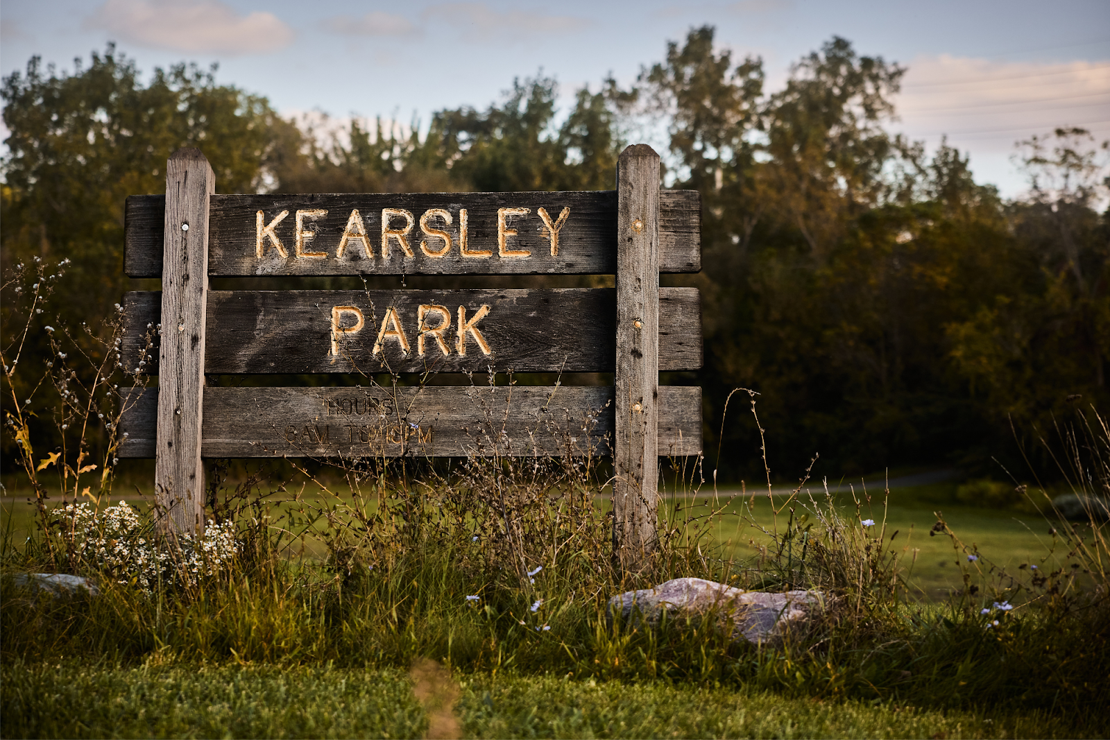 Cut grass, rocks, and withering flowers surround the Kearsley Park sign on Flint's east side on Sept. 28, 2024. (Bryce Mata | Flintside.com)