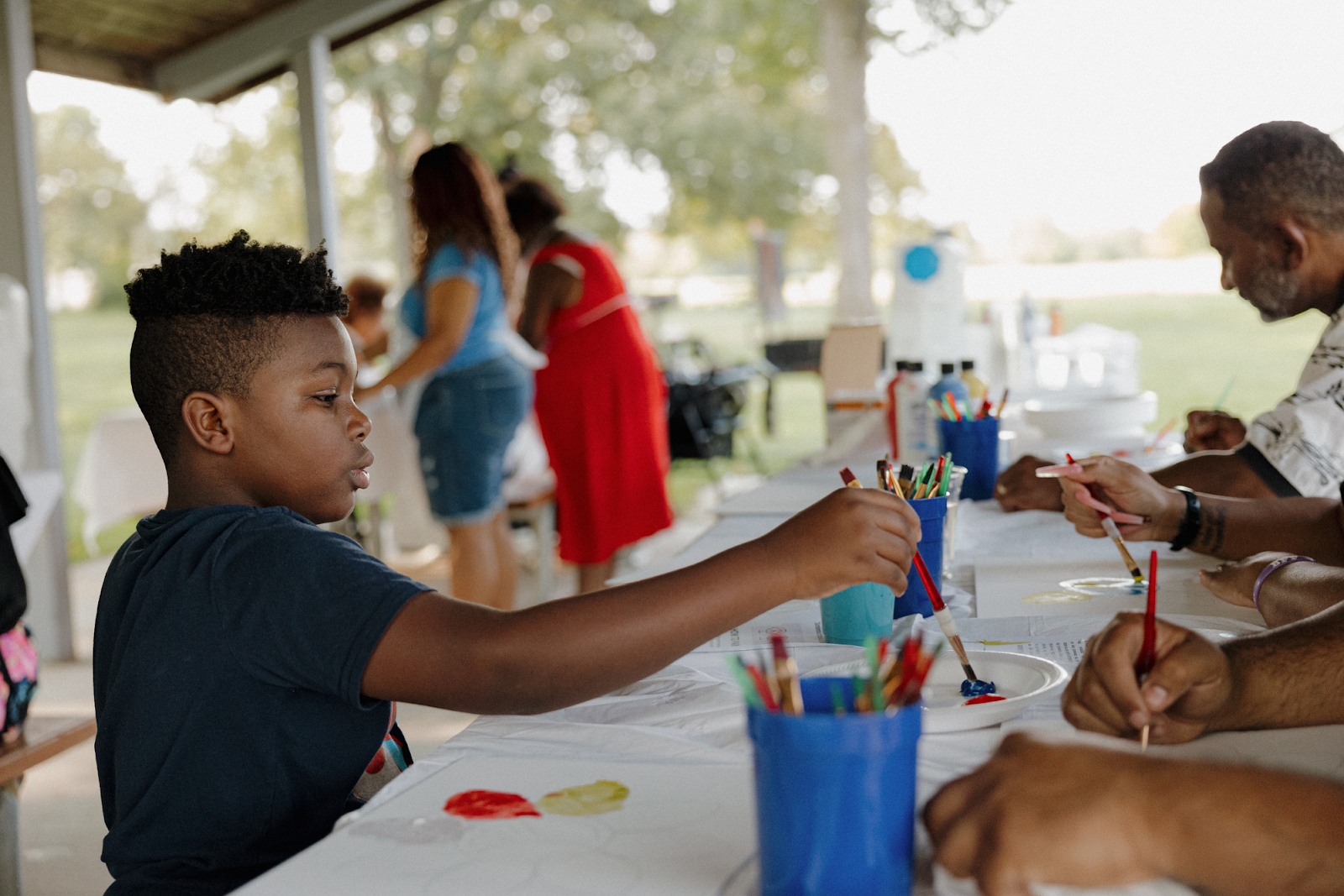 A boy prepares his brush for the next stroke of paint at 'Art in the Park' on Sept. 15, 2024. (Anthony Summers | Flintside.com)