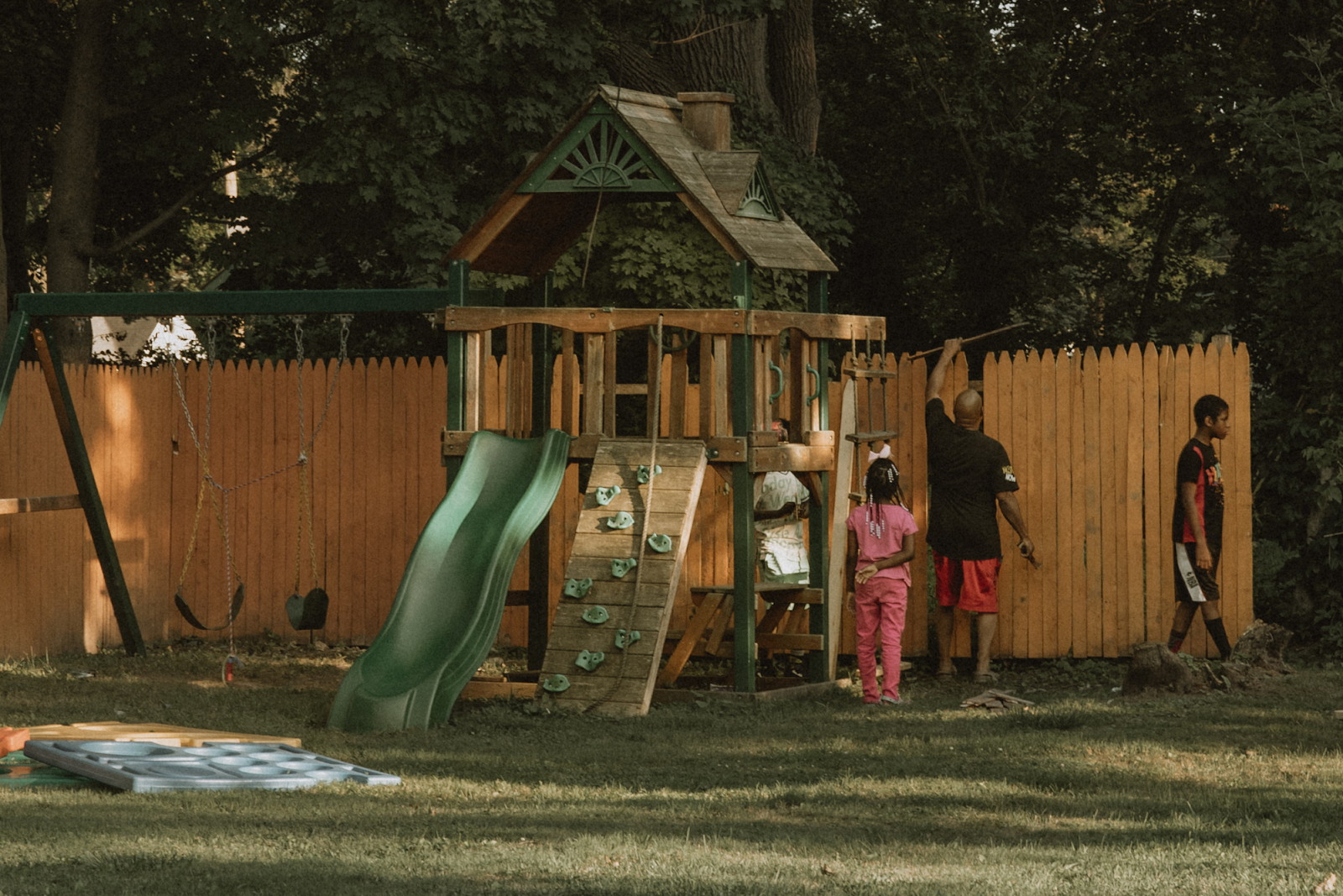 Pictured on Aug. 12, 2024, a father shows his children how to replace their fence in Civic Park. (Anthony Summers | Flintside.com)