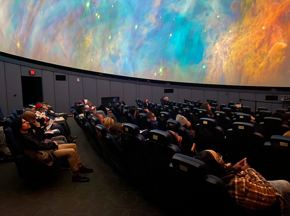 Attendees enjoy music under a vivid planetary backdrop at Jon Connor's listening party for his newest album "III" at Longway Planetarium in Flint on Wednesday, Jan. 24, 2024. (Tia Scott | Flintside)