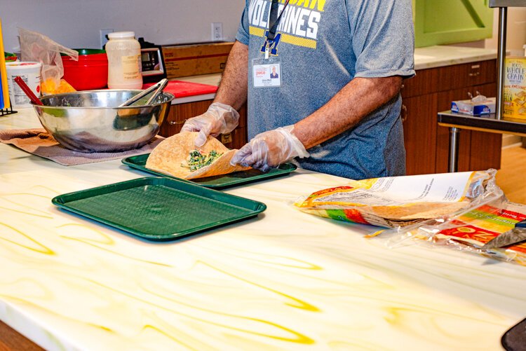 Chris Elliott prepares the turkey and cheese wraps with care. Both locations make the same menu items using the same core ingredients; each chef using their own recipe.