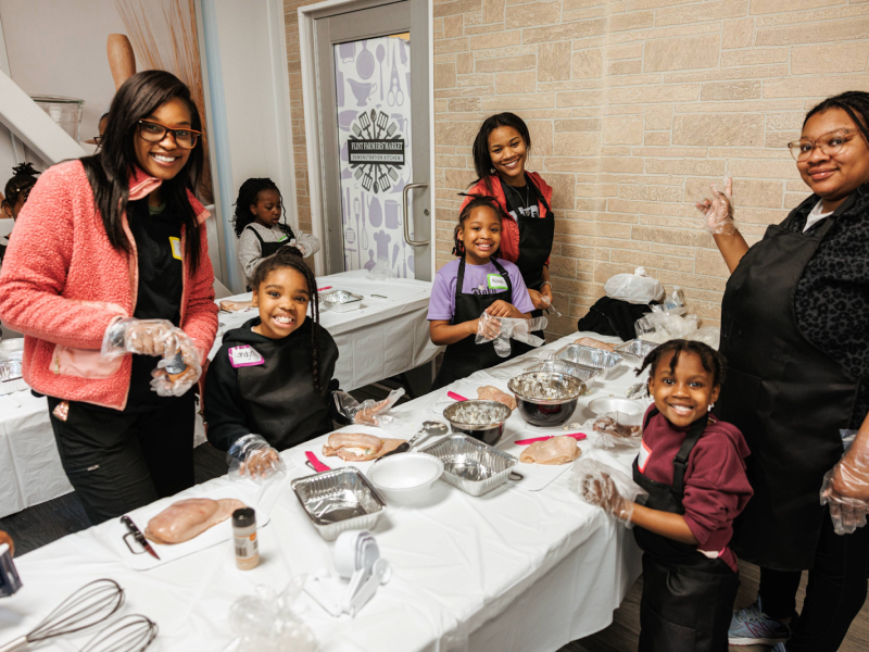 Mothers and daughters pose during Mission Possible's NourisHER class at the Flint Farmers' Market on May 11, 2024.