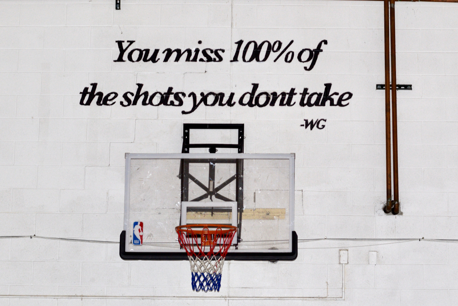 An inspirational quote is painted above a basketball hoop inside the St. Mark gym on Jan. 6, 2024. (Michell Thompson l Flintside.com)