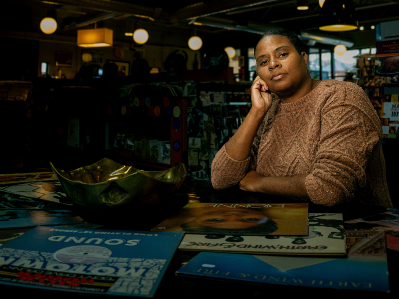 Billie Dantzler sits dignified in front of some of her favorite vinyl records inside Totem Books on Nov. 20, 2023.
