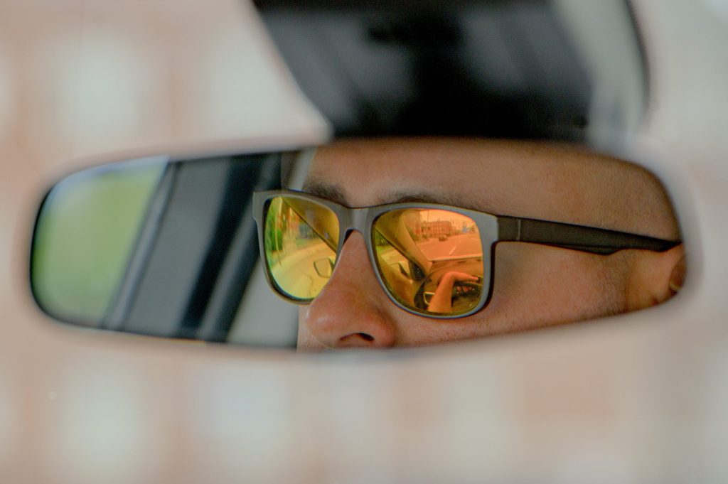 Genesee County Sheriff’s Deputy Christian Bowman, of the GRACE Team, is reflected in the rear-view mirror of his car on Wednesday, Aug. 30, 2023. (Michael Indriolo | Flint Beat)
