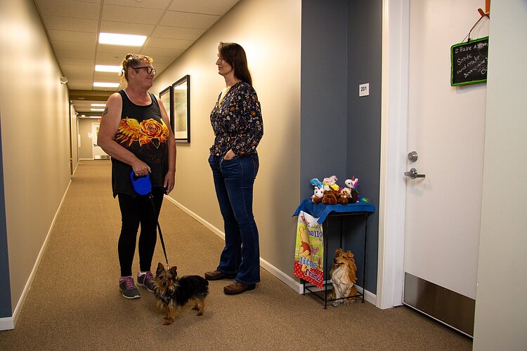 Resident Teresa Brant, her dog, Jack, and Kittie Tuinstra catch up in the hallway at Shelby Trails Apartments.