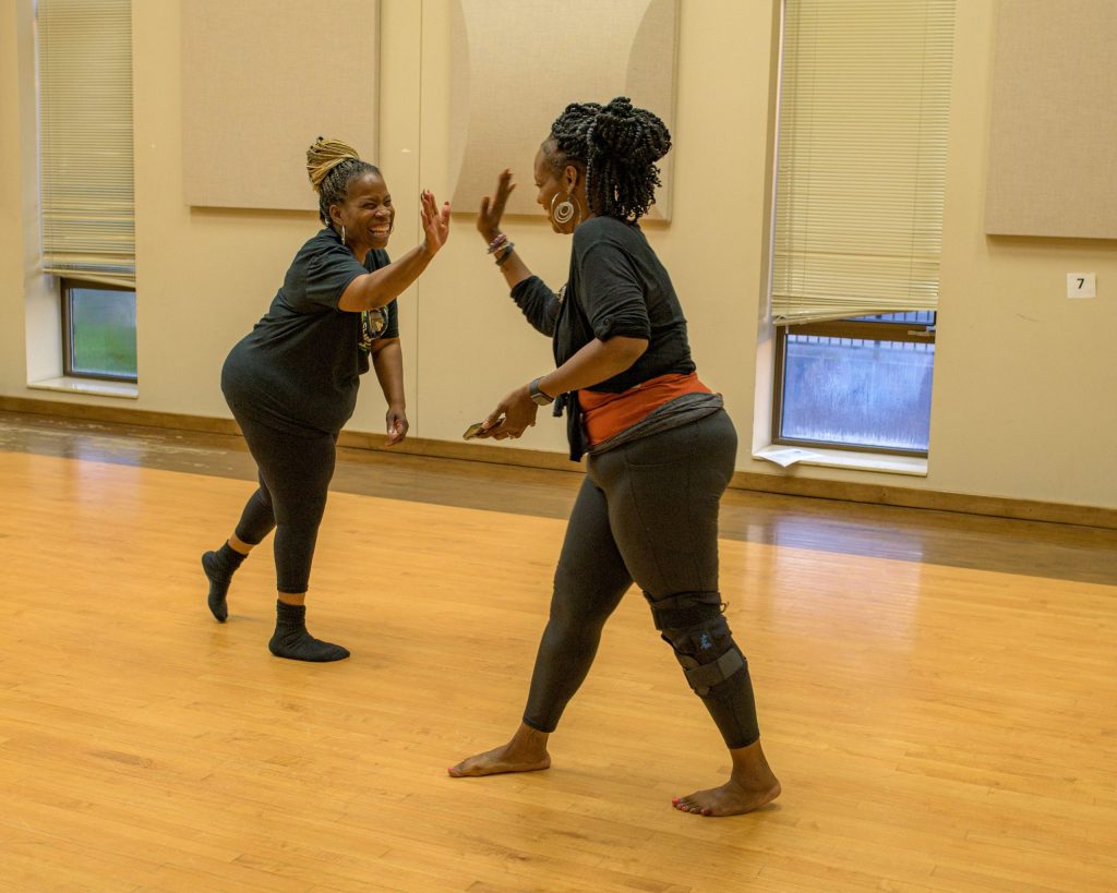 Instructor Tara Holliman (right) high-fives her student Lucy Davis (left) during the Motion in Harmony inclusive dance class at the Flint Institute of Performing Arts on Tuesday, Sept. 19, 2023. (Michael Indriolo | Flint Beat)