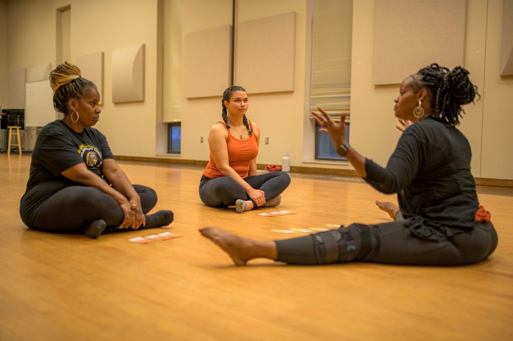 Instructor Tara Holliman (right) talks with her students Lucy Davis (left) and Dezi Snowden (center) about energy flows in the body during the Motion in Harmony inclusive dance class at the Flint Institute of Performing Arts on Tuesday, Sept. 19, 2023. (Michael Indriolo | Flint Beat)