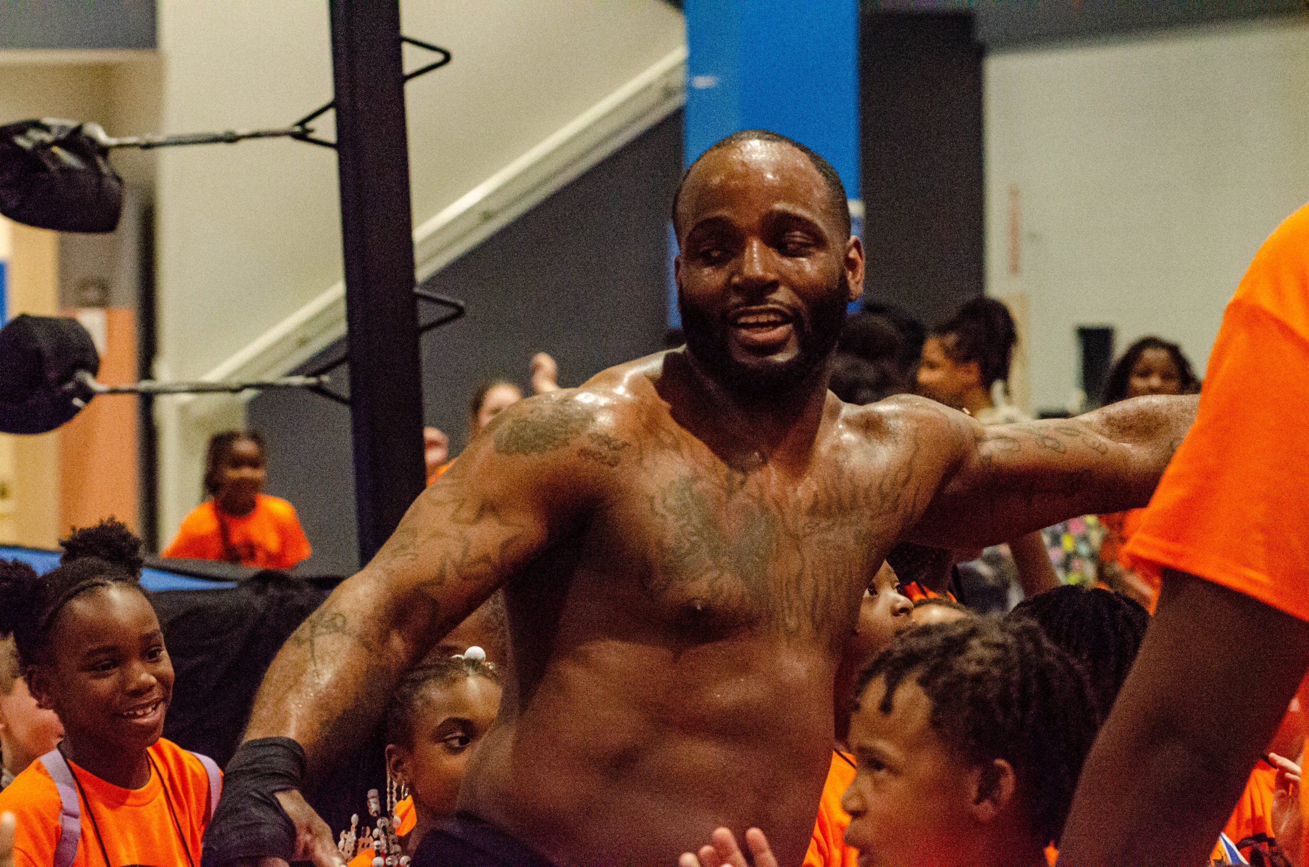 Excited kids gather around a pro-wrestler during the 'Lockdown Pro Wrestling Fundraiser' at Sylvester Broome Empowerment Village on Thursday, July 13, 2023. (Rayford Gray | Flintside)