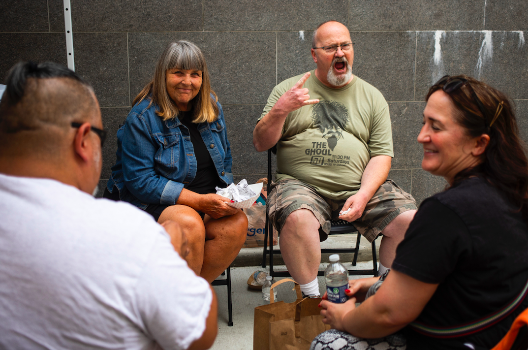 Steve Reddy of Flint, center right, and Lyn Pruett of Grand Blanc, center left, pose for a photo as hundreds of people gather in downtown Flint's Buckham Alley for Alley Fest on Saturday, July 8, 2023. (Katy Kildee | Flintside)
