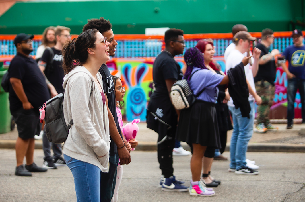 Kaitlyn Werkheiser of Grand Blanc laughs while listening to Caleb Robinson + Reaching's performance as hundreds of people gather in downtown Flint's Buckham Alley for Alley Fest on Saturday, July 8, 2023. (Katy Kildee | Flintside)