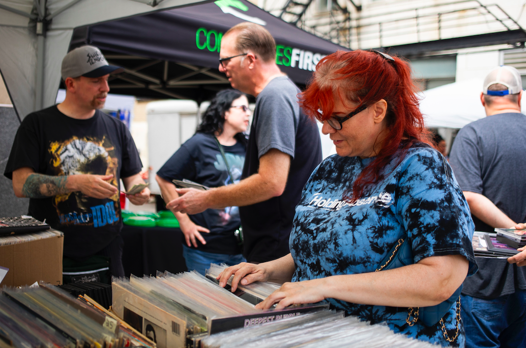 Gidget Arcand of Burton flips through records as hundreds of people gather in downtown Flint's Buckham Alley for Alley Fest on Saturday, July 8, 2023. (Katy Kildee | Flintside)