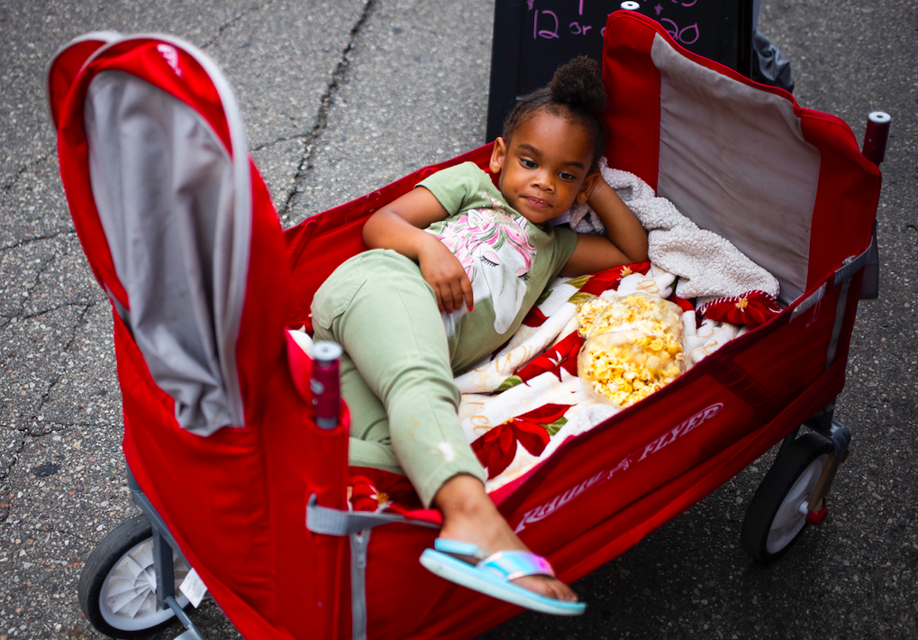 Lauren Hilliard of Beecher, 4, relaxes in a wagon as hundreds of people gather in downtown Flint's Buckham Alley for Alley Fest on Saturday, July 8, 2023. (Katy Kildee | Flintside)
