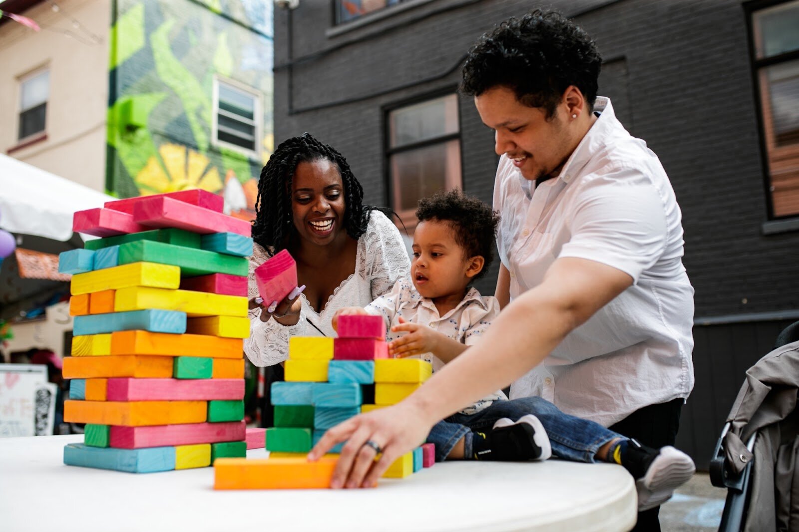 Carrie and Derrick Newman play outdoor Jenga with their son Judah, 2, during the Latinx Technology & Community Center’s Cinco de Mayo celebration on Friday, May 5, 2023, in Buckham Alley in downtown Flint. (Jenifer Veloso | Flintside)
