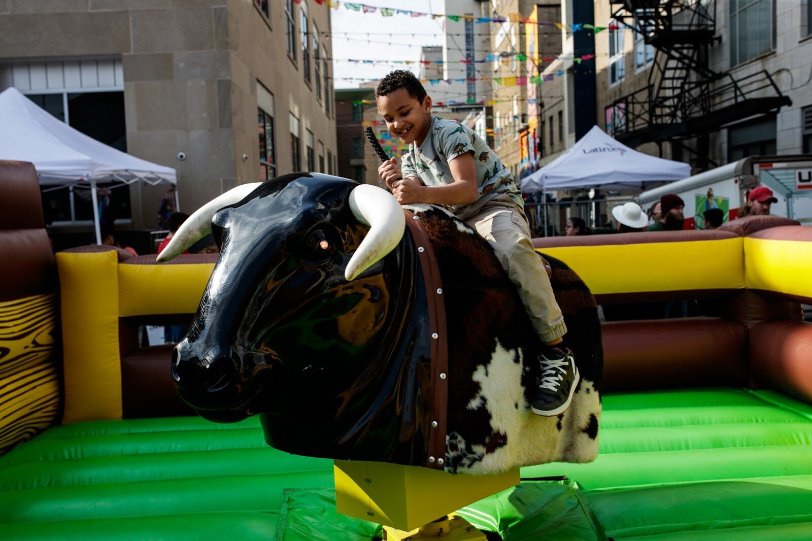 A child enjoys riding a mechanical bull during the Latinx Technology & Community Center’s Cinco de Mayo celebration on Friday, May 5, 2023, in Buckham Alley in downtown Flint. (Jenifer Veloso | Flintside)
