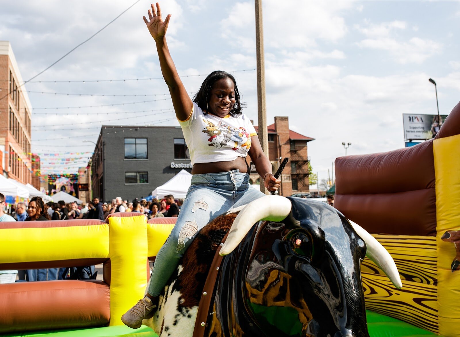 A young woman takes a ride on a mechanical bull during the Latinx Technology & Community Center’s Cinco de Mayo celebration on Friday, May 5, 2023, in Buckham Alley in downtown Flint. (Jenifer Veloso | Flintside)
