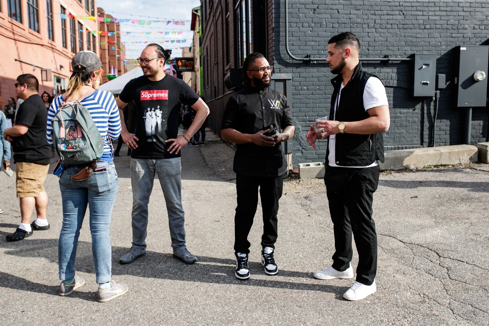 (Right to left) Asa Zuccaro, Wayne the Barber, and Tony Vu talk with one another during the Latinx Technology & Community Center’s Cinco de Mayo celebration on Friday, May 5, 2023, in Buckham Alley in downtown Flint. (Jenifer Veloso | Flintside)
