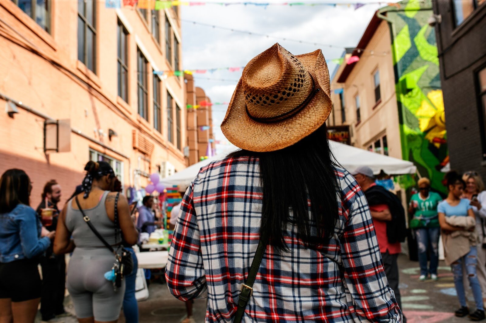 An attendant stands in the alleyway watching the surrounding from the Latinx Technology & Community Center’s Cinco de Mayo celebration on Friday, May 5, 2023, in Buckham Alley in downtown Flint. (Jenifer Veloso | Flintside)
