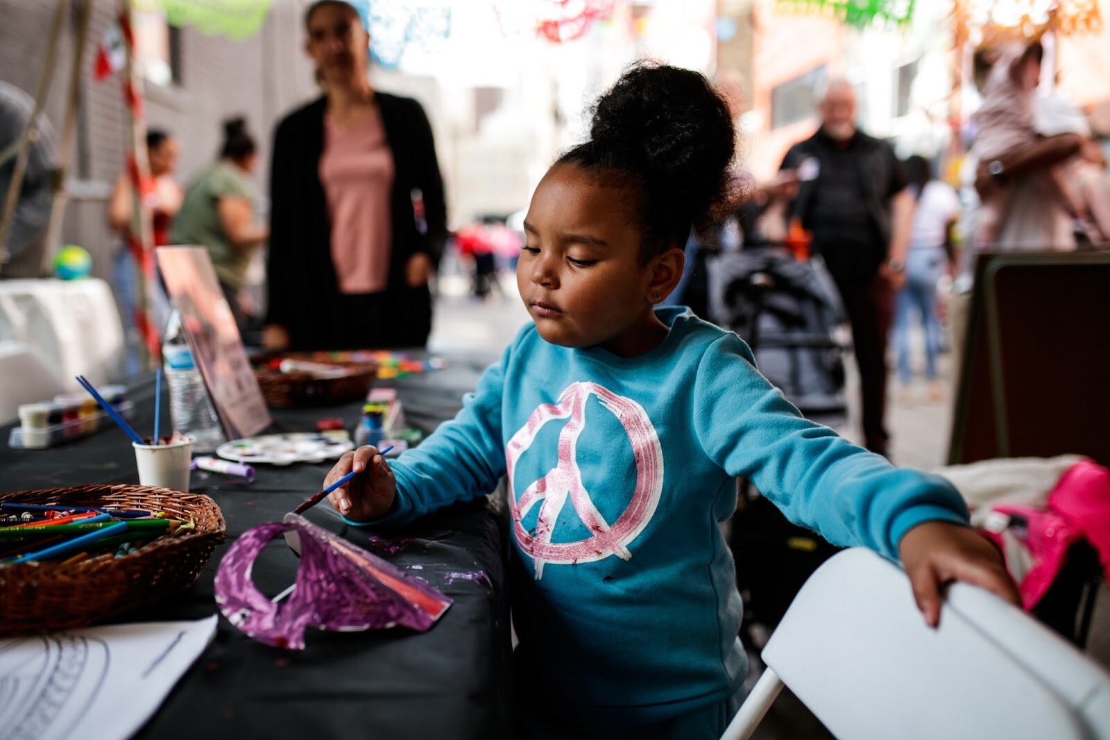 A child enjoys painting at the craft table during the Latinx Technology & Community Center’s Cinco de Mayo celebration on Friday, May 5, 2023, in Buckham Alley in downtown Flint. (Jenifer Veloso | Flintside)
