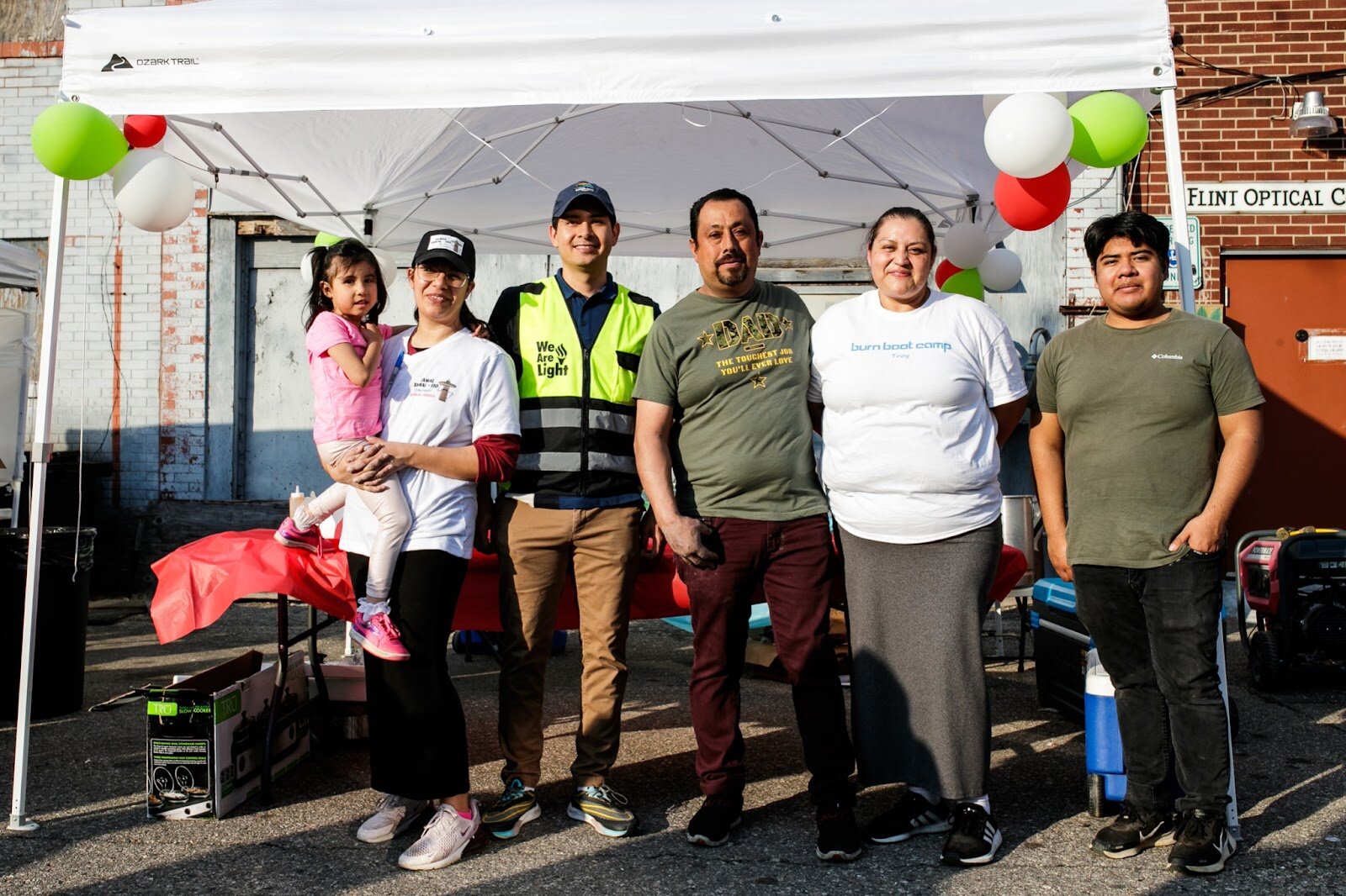 A family stands together in front of their vendor's booth for fresh tamales during the Latinx Technology & Community Center’s Cinco de Mayo celebration on Friday, May 5, 2023, in Buckham Alley in downtown Flint. (Jenifer Veloso | Flintside)
