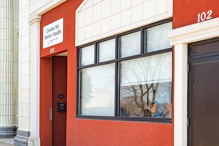 Staff wave from inside the Center for Better Health and Wellness.
