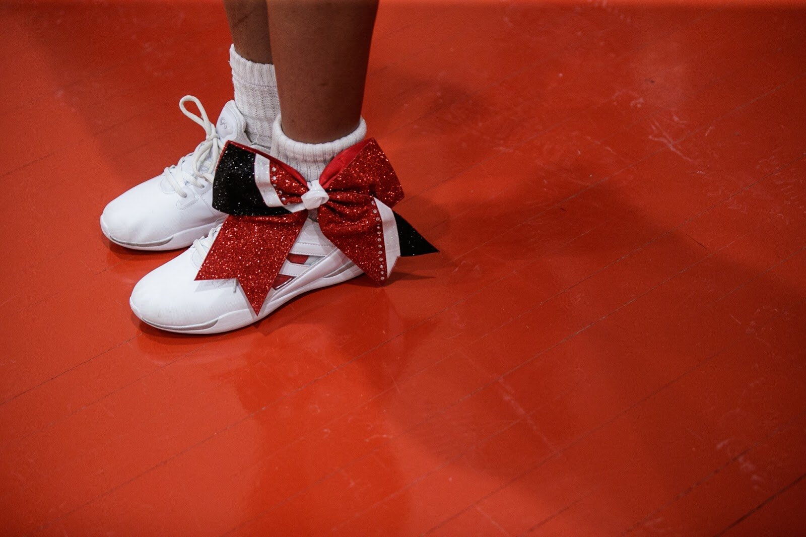 Beecher varsity cheerleader stands on the sideline with a bright red bow during the boys' varsity basketball game on Saturday, Feb. 18, 2023, at the Moses Lacey Fieldhouse in Mount Morris. Beecher defeated Hamady 48-43. (Jenifer Veloso | Flintside)
