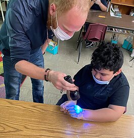 Third-grade students at Neinas Dual Language Learning Academy learning about the importance of proper hand washing and experimenting with glowing germs.