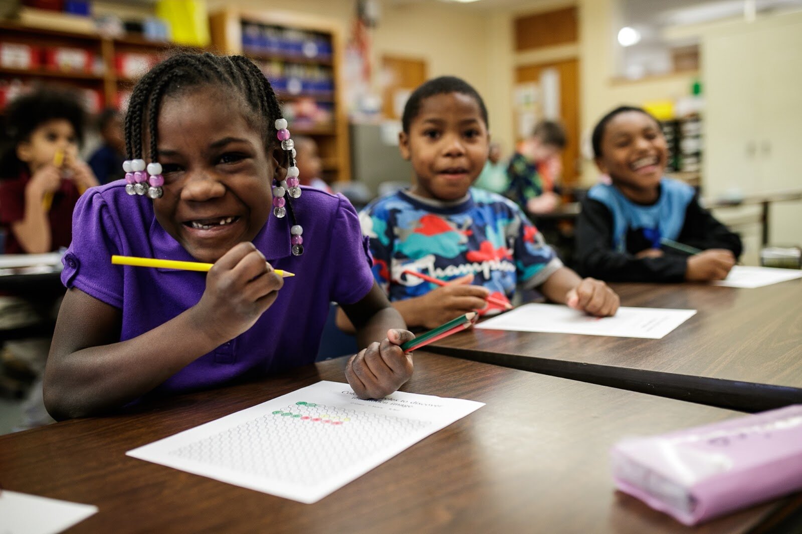 First-grade Freeman scholars smile and laugh as they listen for their names to be called for their Christmas gift bags during Freeman Elementary’s holiday celebration of literacy and reading comprehension on Friday, Dec. 16, 2022. (Jenifer Veloso | Flintside
