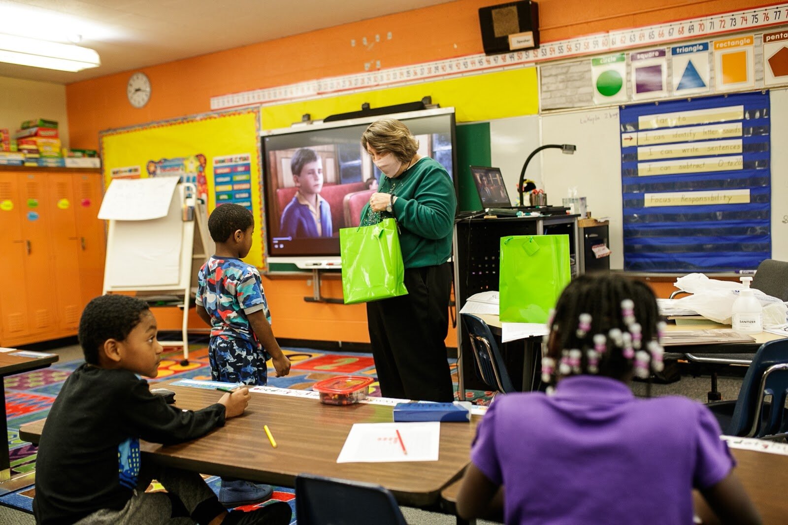 First-grade teacher Mrs. Sandra Baird delivers a Christmas gift bag to one of her students during Freeman Elementary’s holiday celebration of literacy and reading comprehension on Friday, Dec. 16, 2022. (Jenifer Veloso | Flintside)

