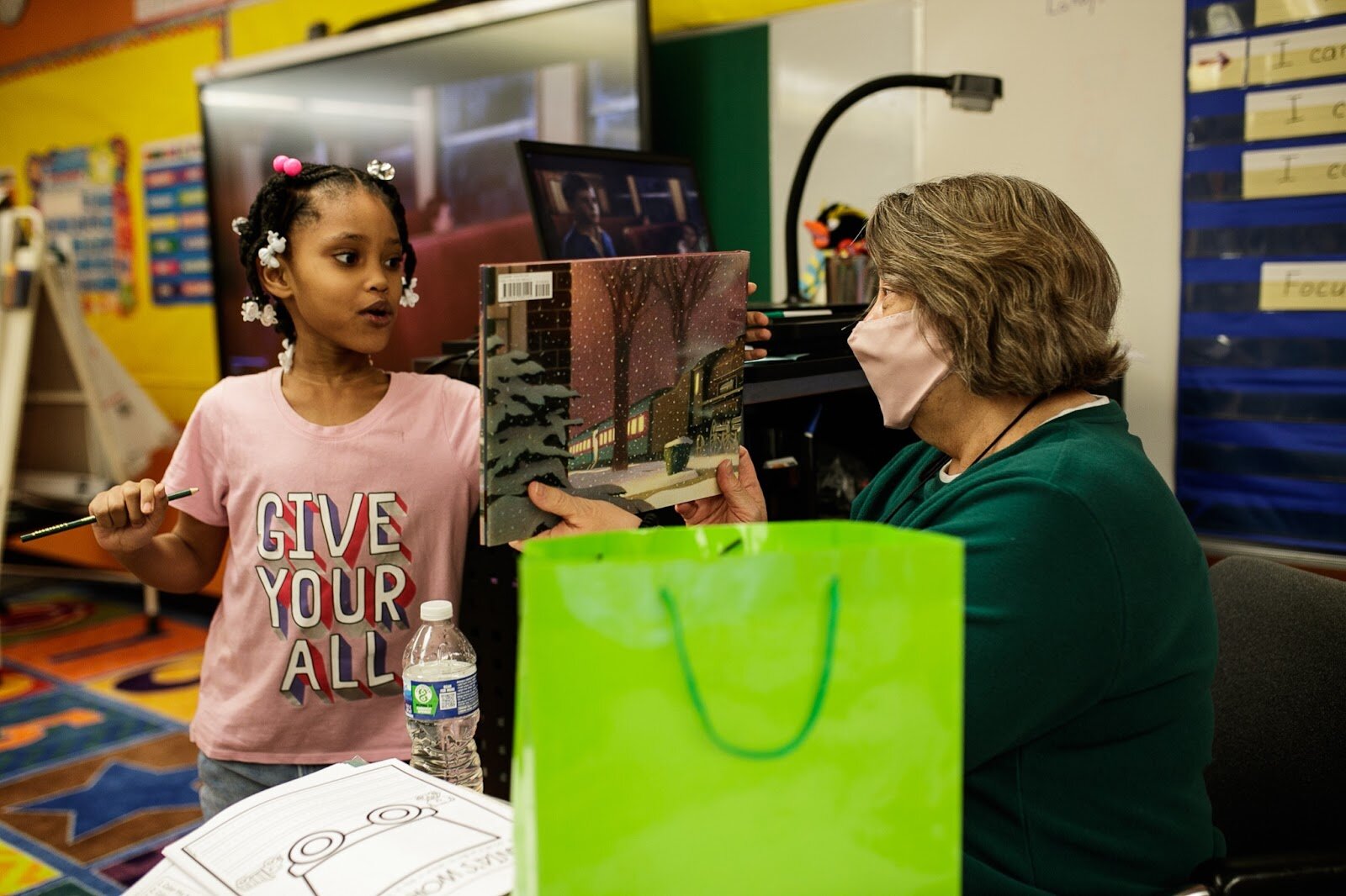 First-grade teacher Mrs. Sandra Baird delivers a Christmas gift bag to one of her students during Freeman Elementary’s holiday celebration of literacy and reading comprehension on Friday, Dec. 16, 2022. (Jenifer Veloso | Flintside)
