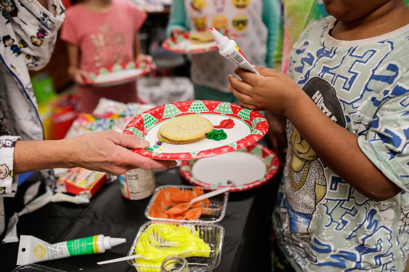 Third-grade teacher Mrs. Curtis helps students pick out first for Christmas cookies during Freeman Elementary’s holiday celebration of literacy and reading comprehension on Friday, Dec. 16, 2022. (Jenifer Veloso | Flintside)
