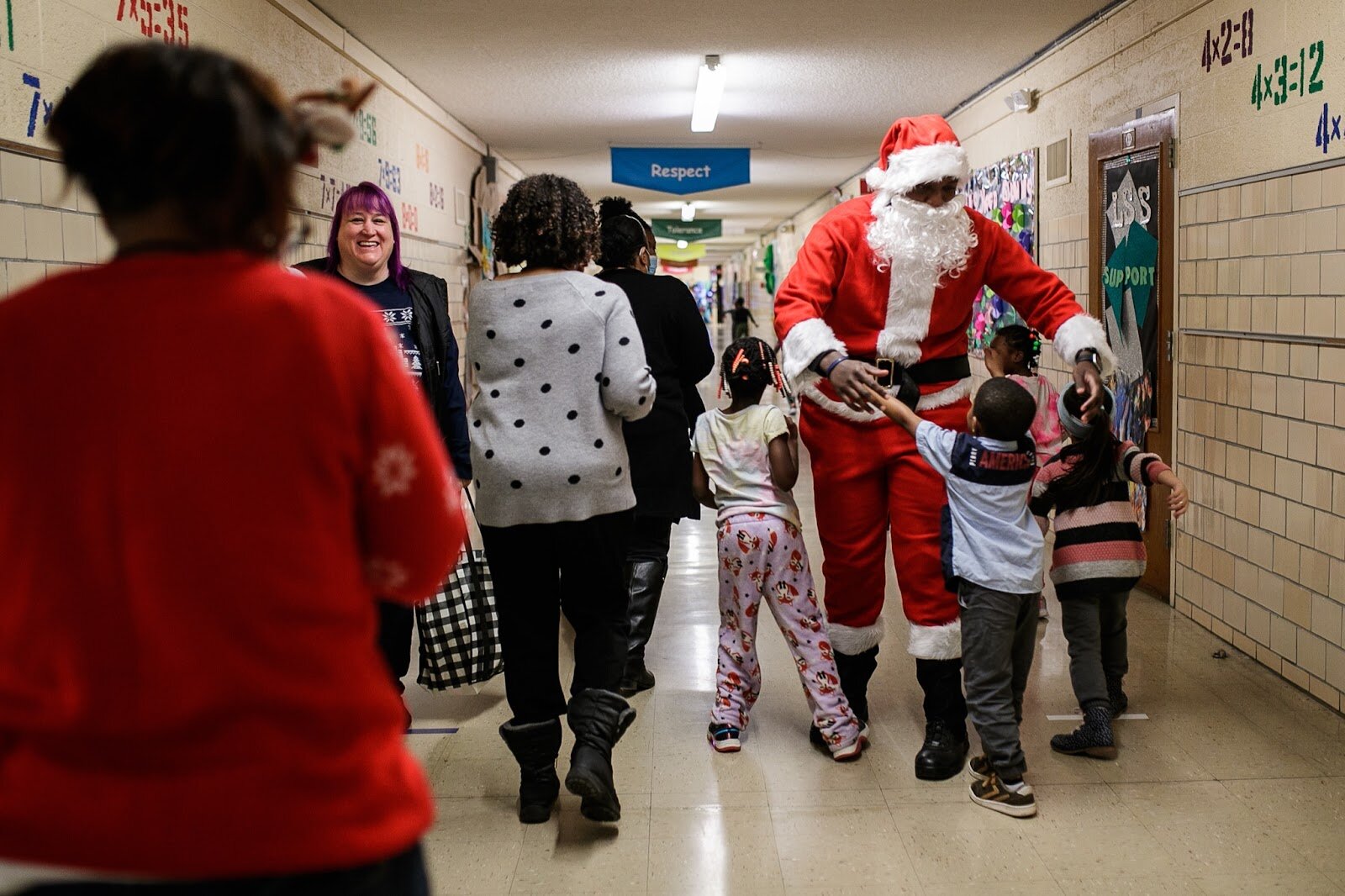 Genesee County Sheriff Deputy Blanding dressed as Santa Clause is hugged and welcomed by students during Freeman Elementary’s holiday celebration of literacy and reading comprehension on Friday, Dec. 16, 2022. (Jenifer Veloso | Flintside)
