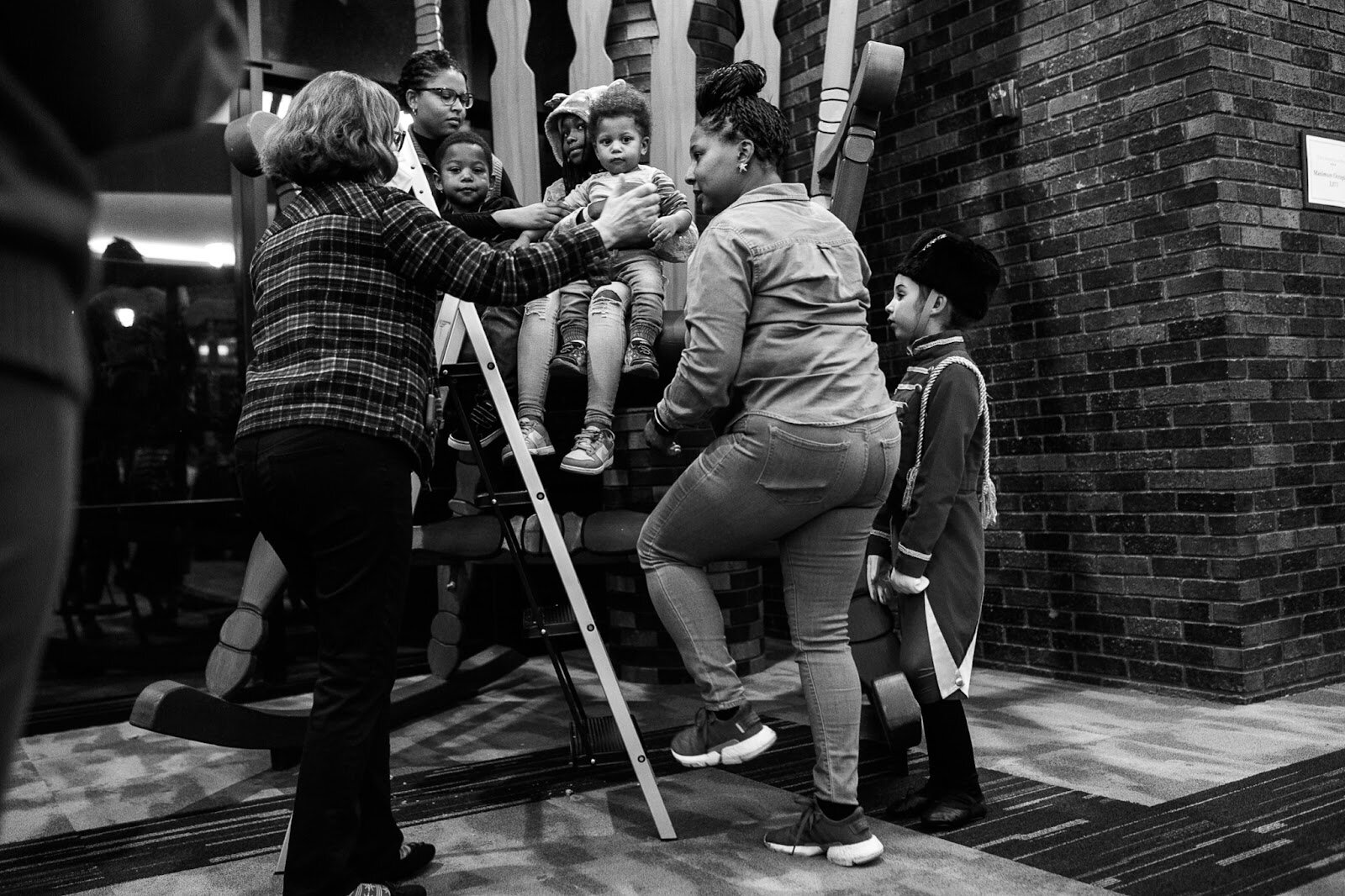 Guests prepare to take a picture on the giant Nutcracker rocking chair inside of the Flint Institute of Music during the College Cultural area’s 37th Annual Holiday Walk in Flint on Tuesday, Dec. 6, 2022. (Jenifer Veloso | Flintside)
