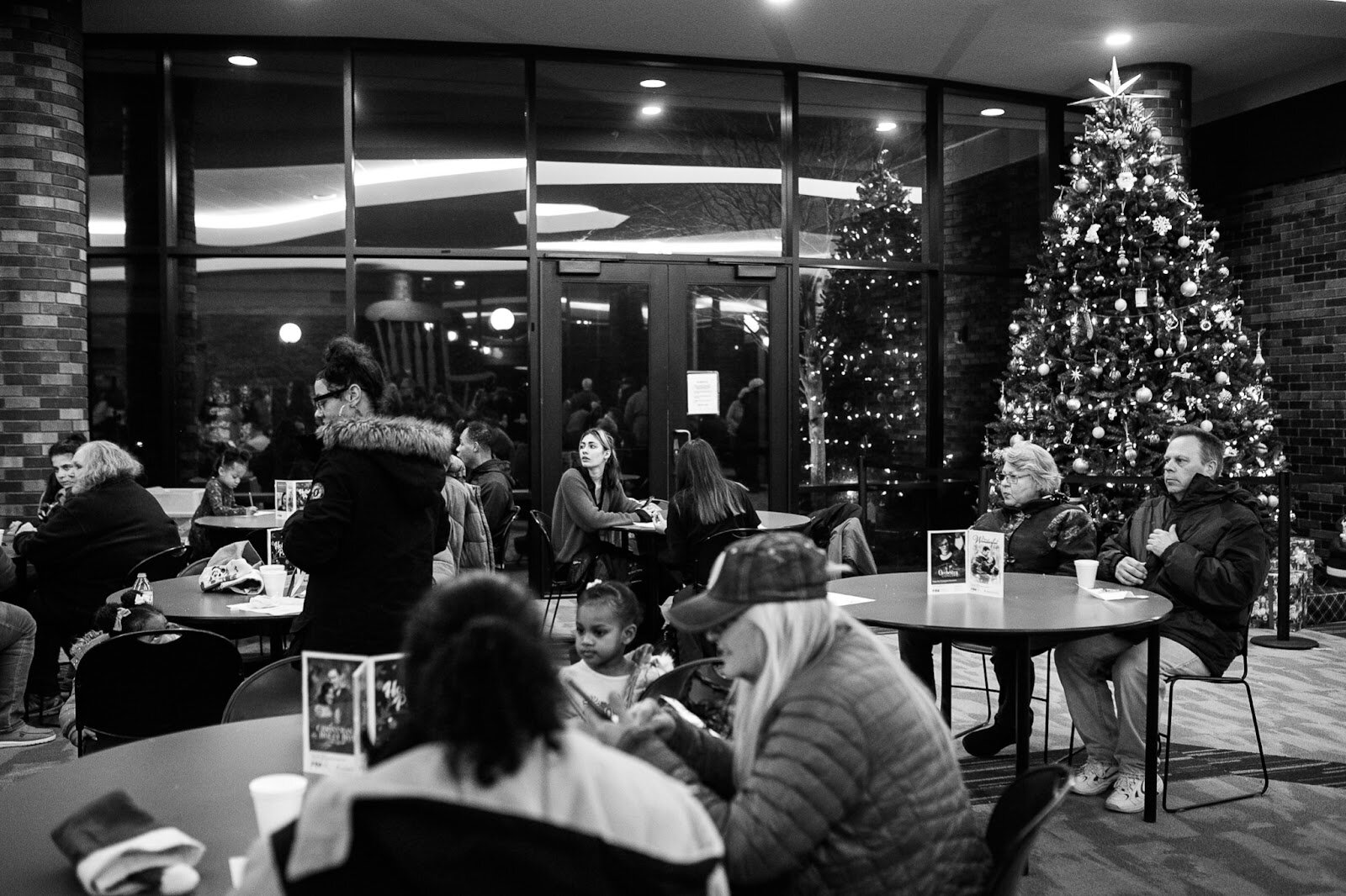 Holiday Walk guests take a seat inside FIM for hot chocolate, cookies and a live wind ensemble performance during the College Cultural area’s 37th Annual Holiday Walk in Flint on Tuesday, Dec. 6, 2022. (Jenifer Veloso | Flintside)
