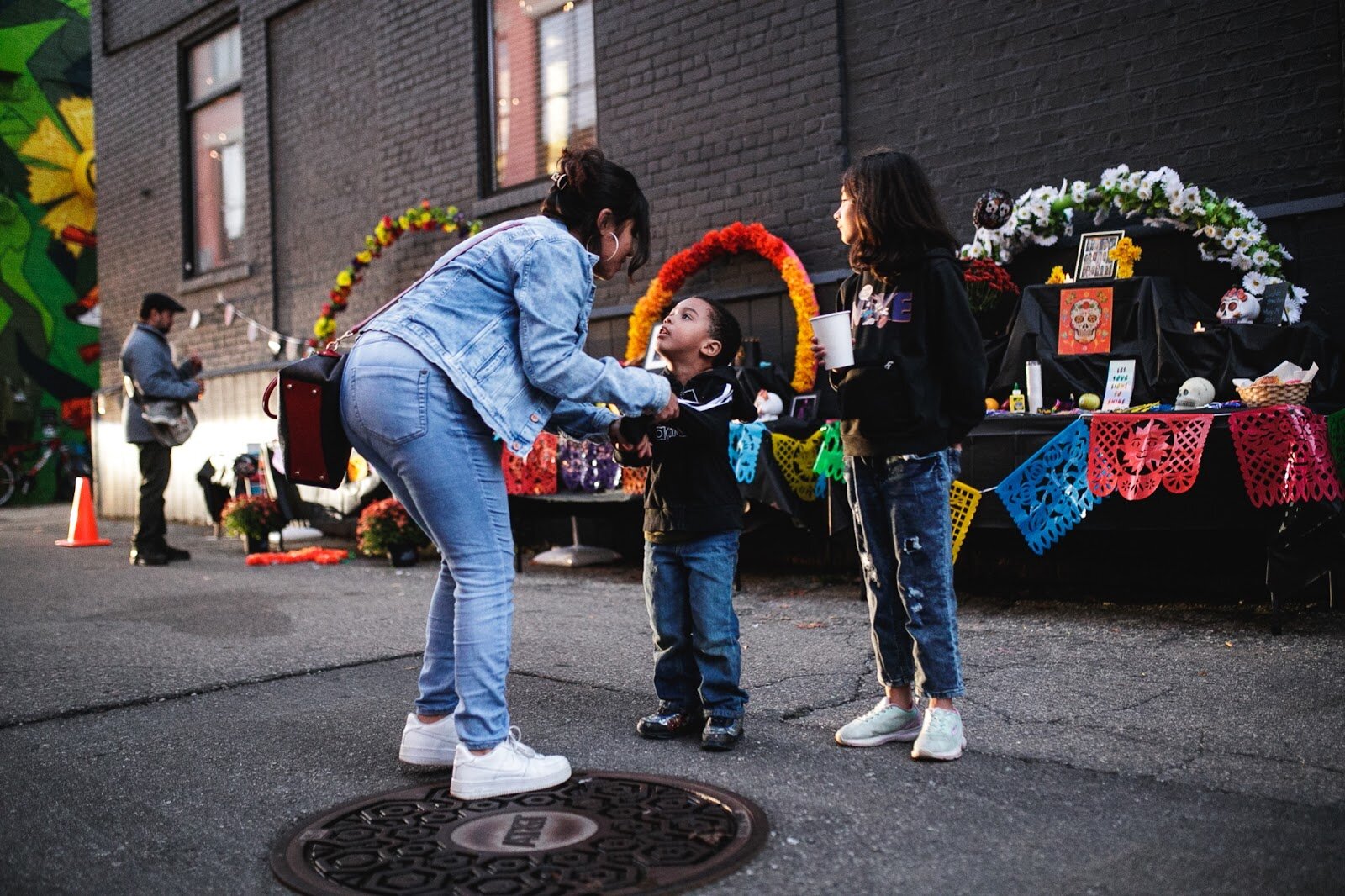 Maricla Franco dances with her son Ezekiel Franko alongside her daughter Nyomi Franco during the Latinx Technology and Community Center's Dia de Los Muertos celebration on Wednesday, Nov. 2, 2022 in downtown Flint. (Jenifer Veloso | Flintside)