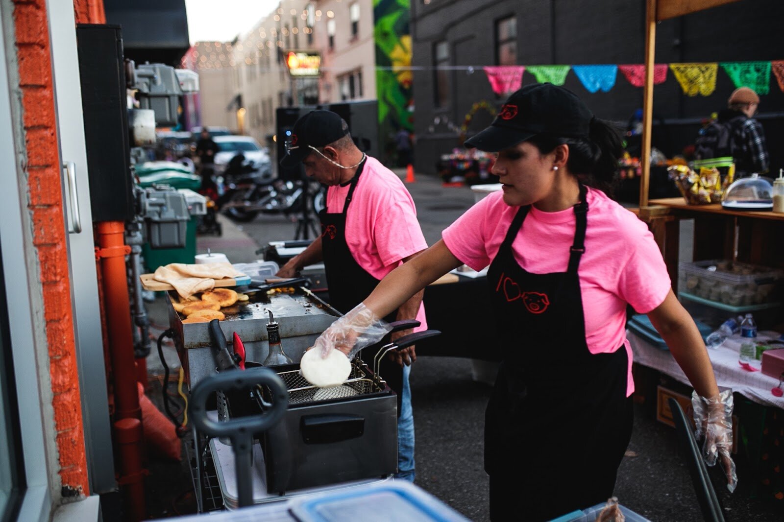Aliza Mendosa and Daniel Solorzano, from I <3 Pig, work together to fry and cook fresh arepas during the Latinx Technology and Community Center's Dia de Los Muertos celebration on Wednesday, Nov. 2, 2022 in downtown Flint. (Jenifer Veloso | Flintside)