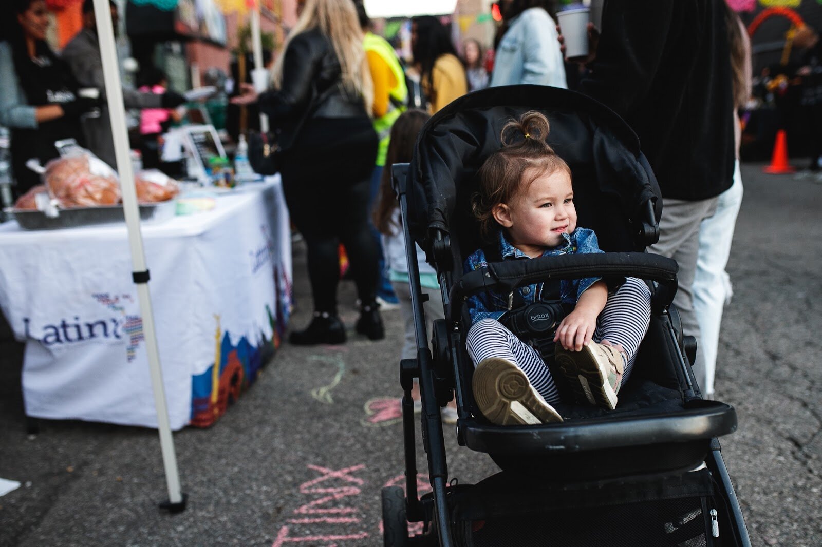 A child smiles while sitting in a stroller during the Latinx Technology and Community Center's Dia de Los Muertos celebration on Wednesday, Nov. 2, 2022 in downtown Flint. (Jenifer Veloso | Flintside)