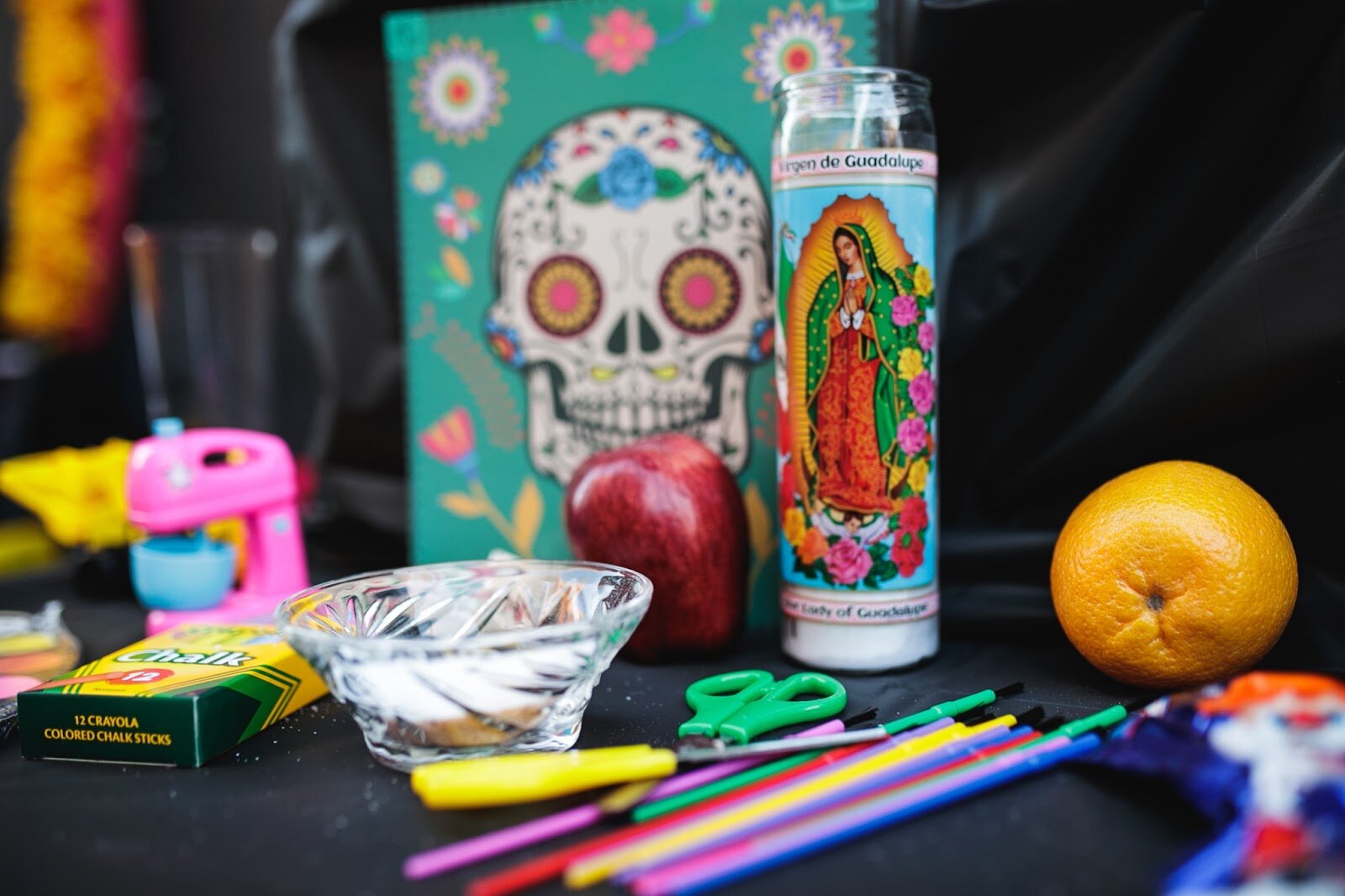An ofrenda is decorated with children's art supplies, fresh fruit, toys, and a candle sits on display in memory of the children killed in the Uvalde shooting during the Latinx Technology and Community Center's Dia de Los Muertos celebration on Wednesday, Nov. 2, 2022 in downtown Flint. (Jenifer Veloso | Flintside)