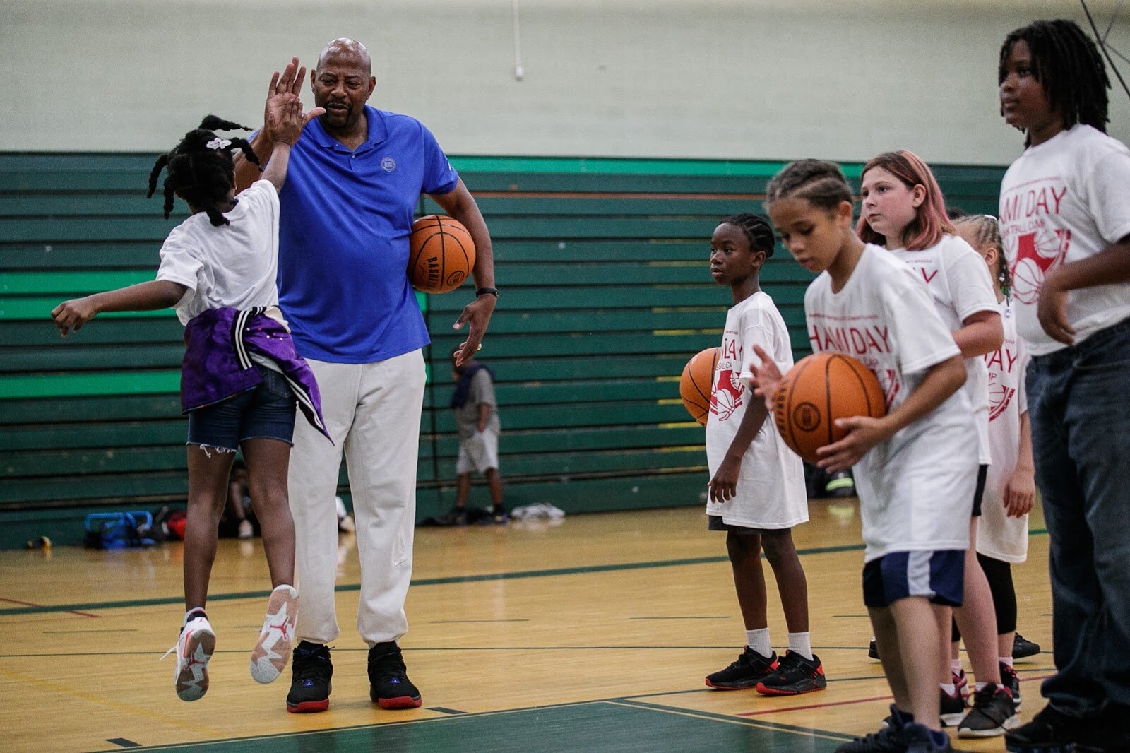 NBA Champion Earl "The Twirl" Cureton high-fives an attendant of Hami Day Camp at Northwestern High School in Flint on Friday, Aug. 27, 2022. (Jenifer Veloso | Flintside.com)
