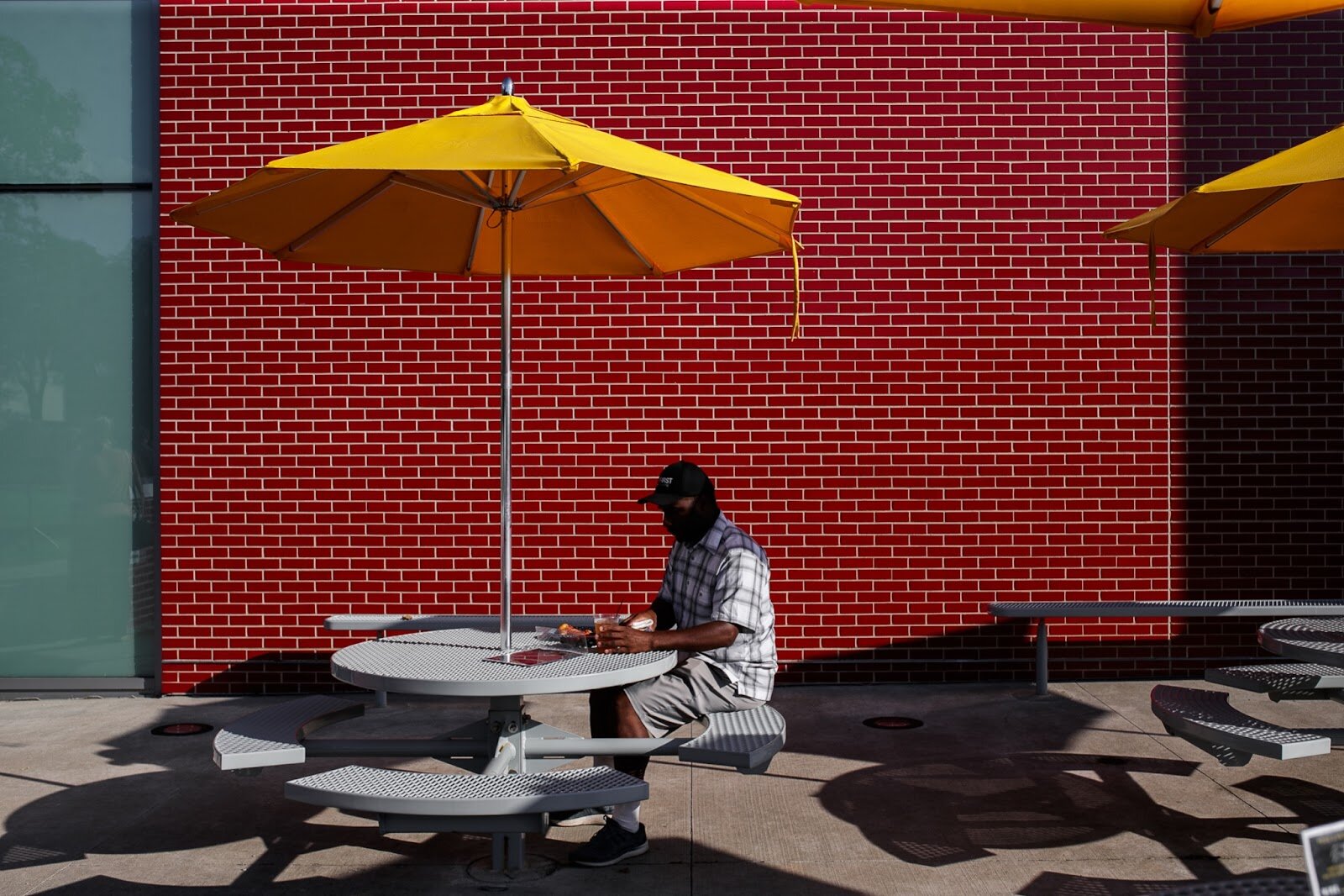 A guest sits at a table to find some shade outside of the Palette Cafe patio during Family Night at 'Late Night at the FIA' on Friday, Aug. 19, 2022. (Jenifer Veloso | Flintside.com)
