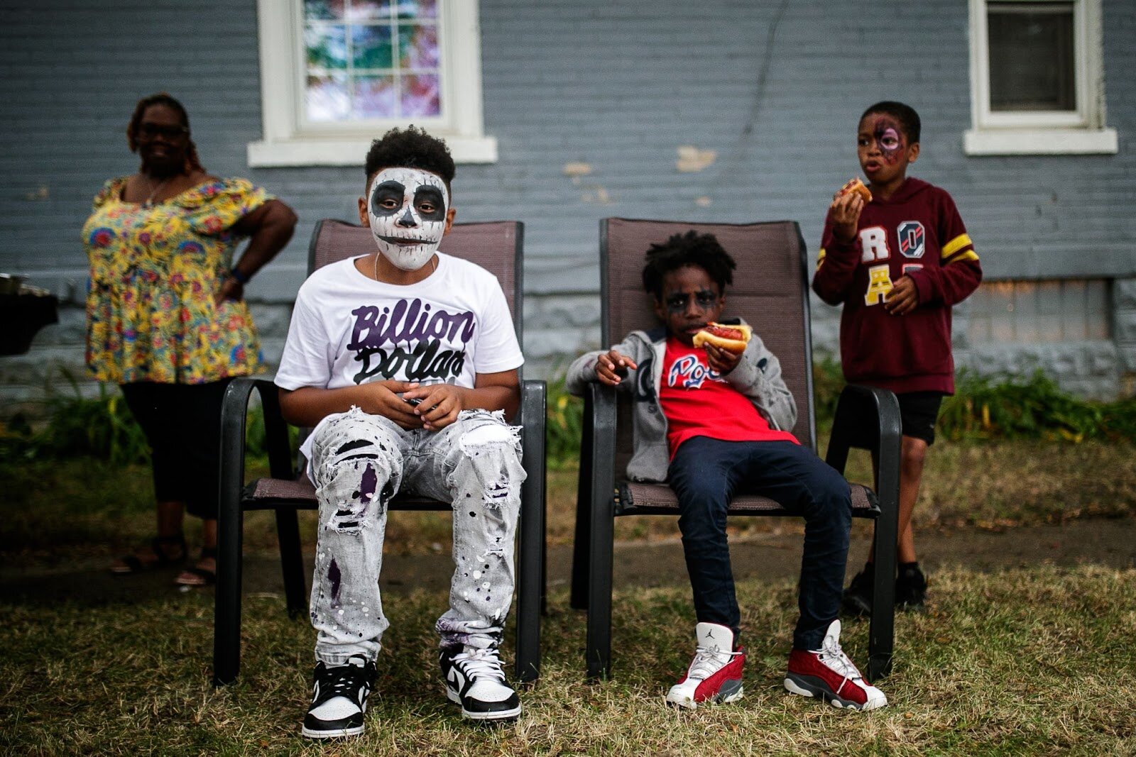 Pictured from left to right; Nicholas Morgan, Zavier Wilson, and Aidan Alston enjoy hotdogs outside their grandmother's house during Porch Fest on Friday, July 15, 2022. (Jenifer Veloso | Flintside)