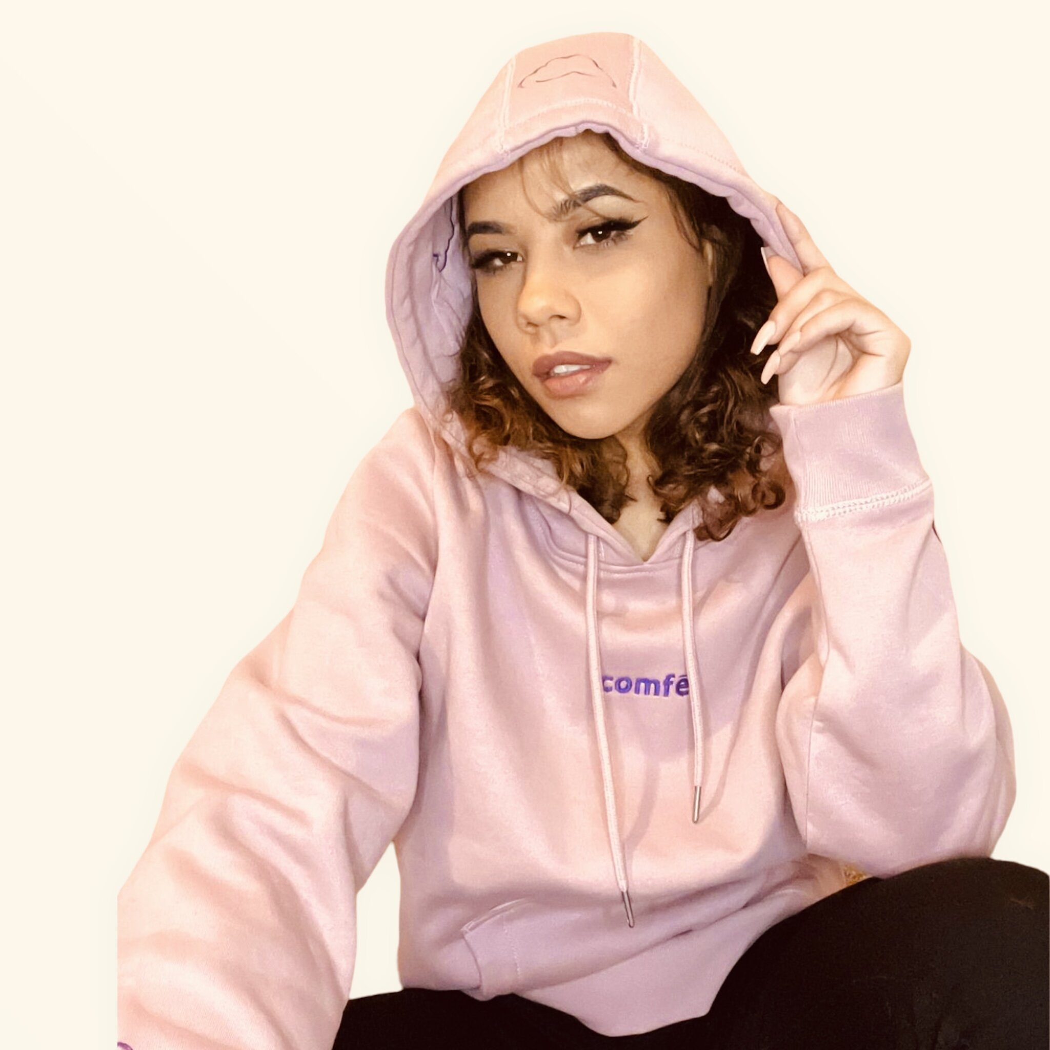 A model cozies up in a light pink and purple hooded sweatshirt exclusively from Comfe.