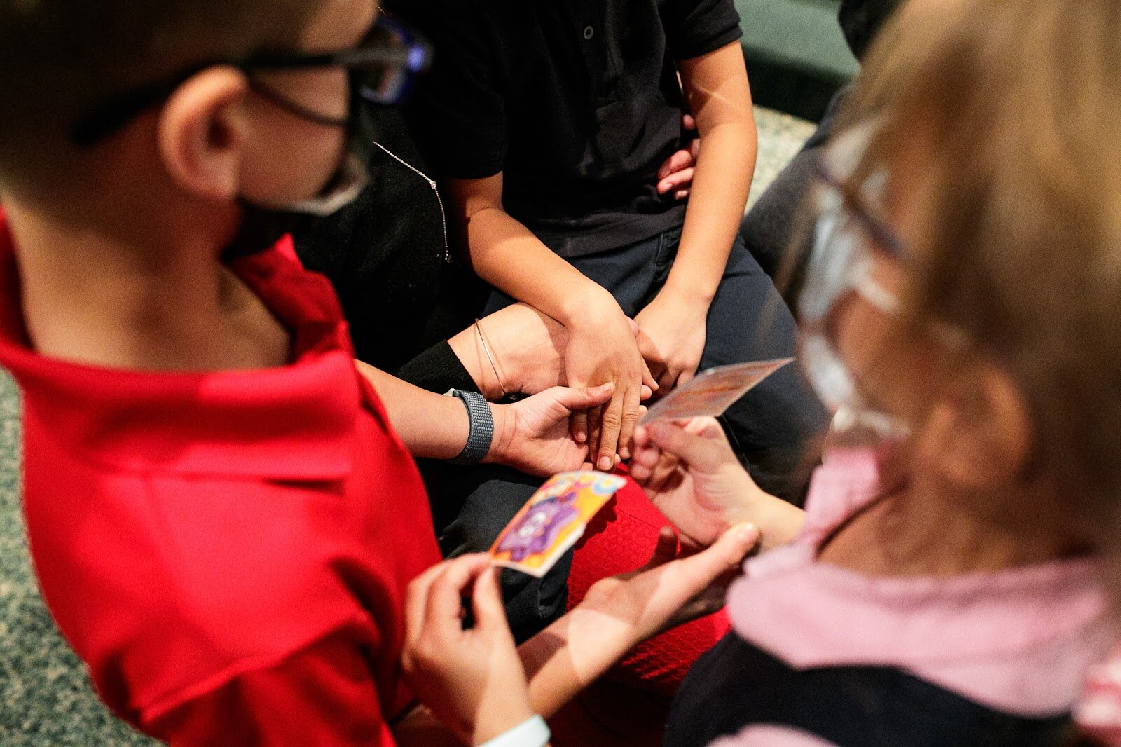 Children hold each other's hands while receiving their first dose of the COVID-19 vaccine.