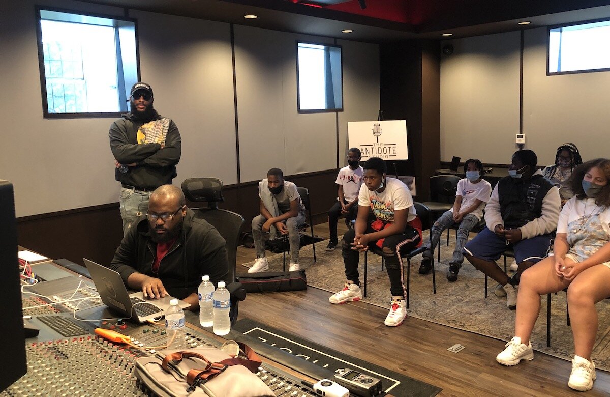 Nygee Gant, lead engineer at The Antidote Studio, plays a track as RushDee listens with students.