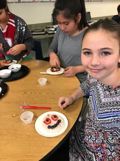 Upper elementary students in the PE-Nut program create faces for their rice cake snack.