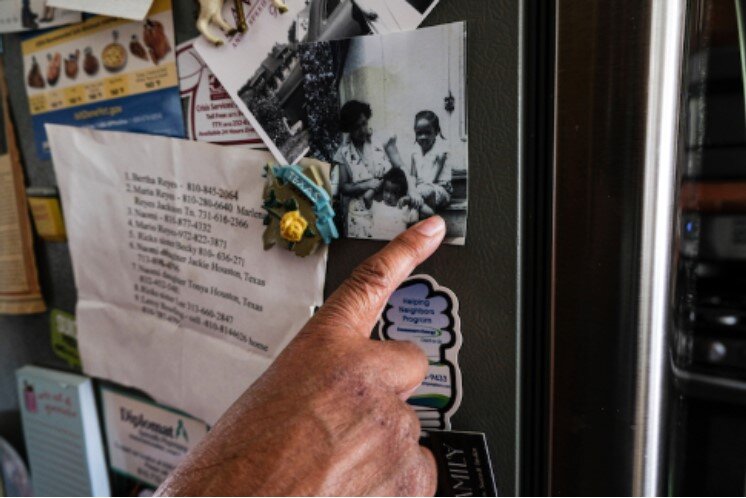 Amongst refrigerator flyers and her neighborhood contacts, Speed points to an older photograph herself seated alongside her mother and younger brother.
