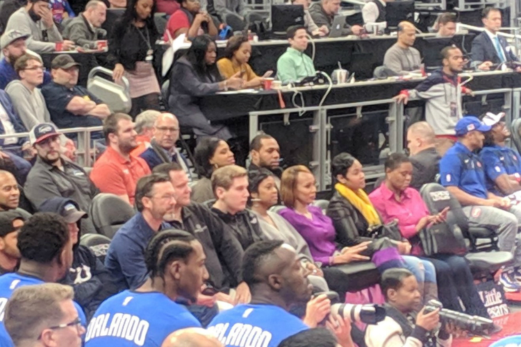Dan Feldman (top center, green shirt), who covers the NBA for NBC Sports, sitting on press row at Little Caesarâs Arena during a Detroit Pistons game.