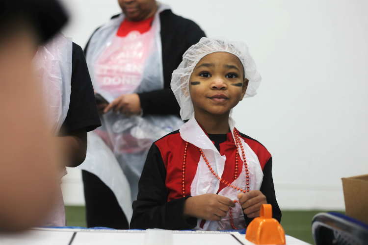 Desmond Suliamar, 5, looks on at the mob of hair nets wearing volunteers as 550 volunteers descended on the Dort Federal Event Center in Flint to fill boxes of food for the hungry.