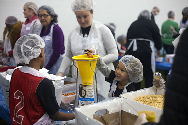 Laylah Johnson, 5, drops dried goods into a funnel to help hungry families at the United Way Food Drive on the Martin Luther King holiday. 